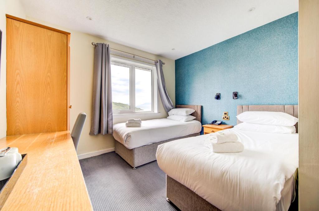 a hotel room with two beds and a window at The Morar Hotel in Morar