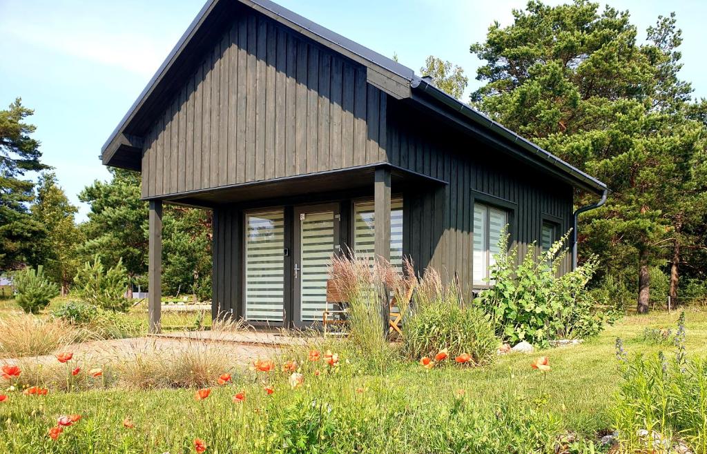 a small black house in a field of flowers at Anna's Home in Jūrmalciems