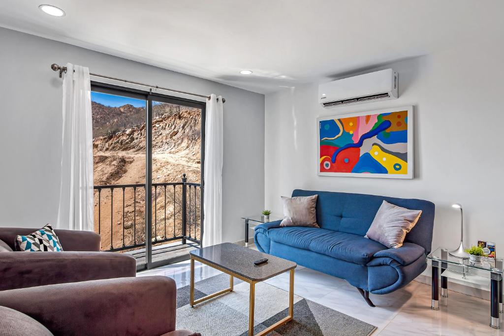 a living room with a blue couch and a window at Morgan Residences 508A in Cabo San Lucas