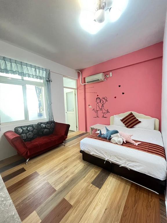 a bedroom with pink walls and a bed and a couch at Rihchun Homestay in Hengchun South Gate