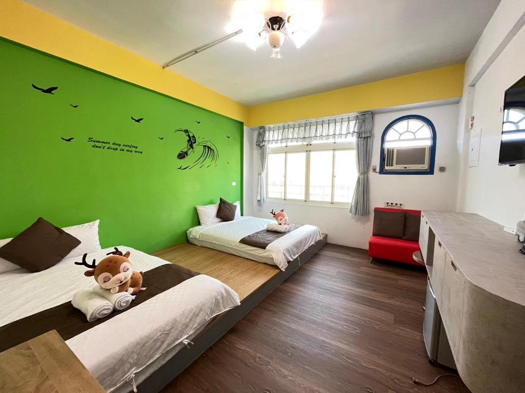 a bedroom with two beds and a green wall at Rihchun Homestay in Hengchun South Gate