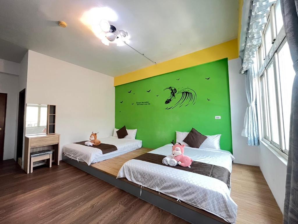 two beds in a room with a green wall at Rihchun Homestay in Hengchun South Gate