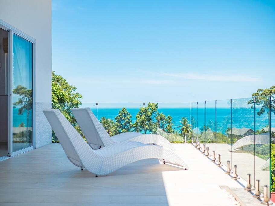 Villa Maviela Sea View 2 Bdr في كوه ساموي: كرسي صالة بيضاء على شرفة مطلة على المحيط