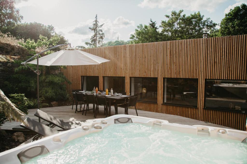 a hot tub in a backyard with a table and an umbrella at Grand loft avec Jacuzzi et Home Cinema in Saint-Brieuc