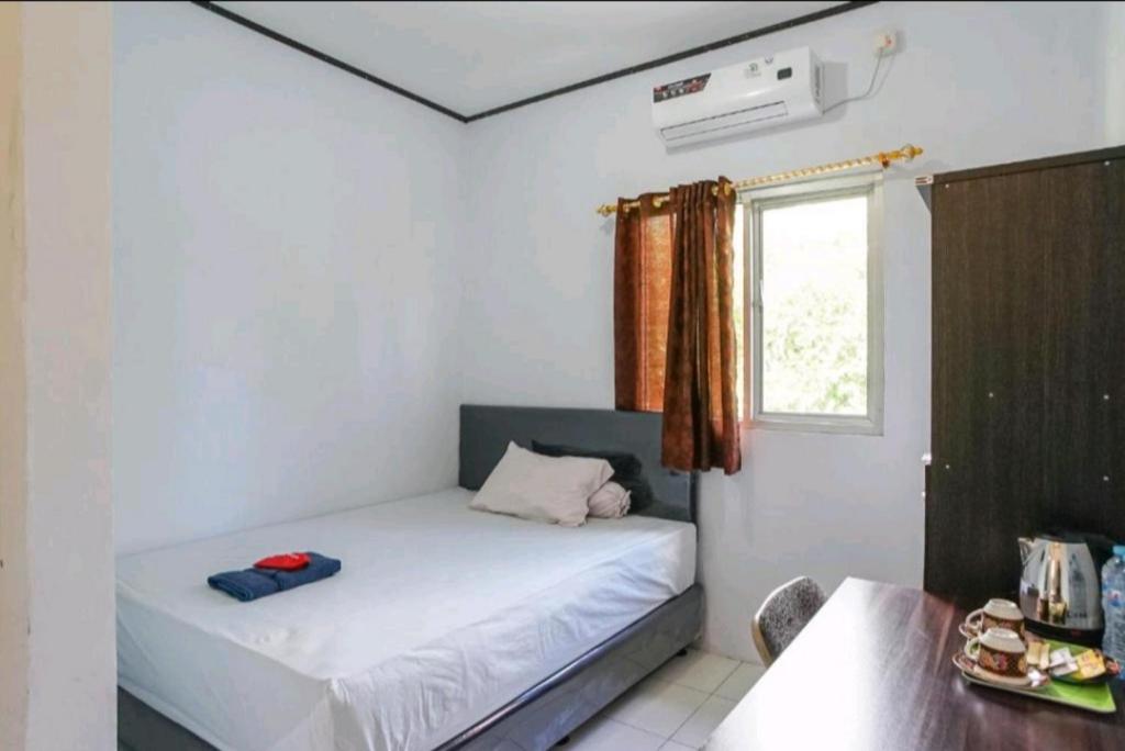 Habitación pequeña con cama y ventana en PAS Residence Sam Ratulangi Airport Mitra RedDoorz, en Mapanget
