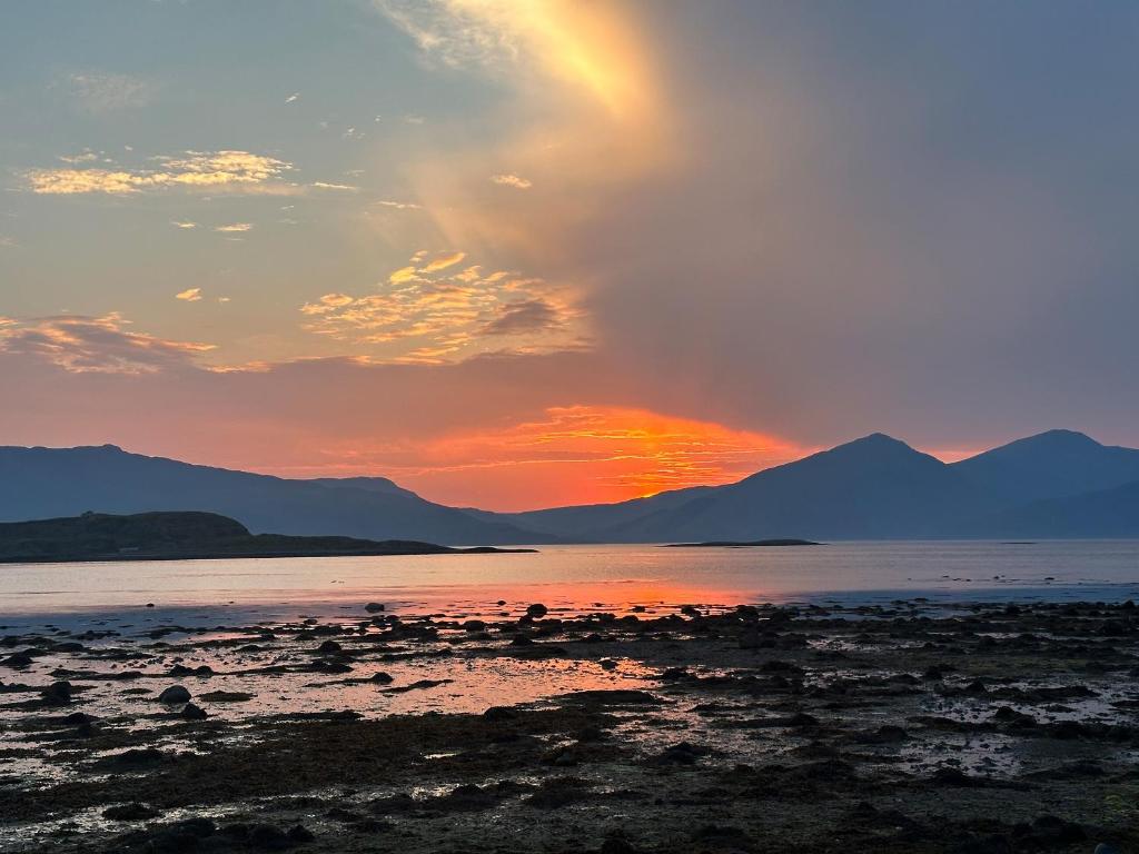 una puesta de sol sobre el agua con montañas en el fondo en Sealladh Apartment - Ukc6792, en Port Appin