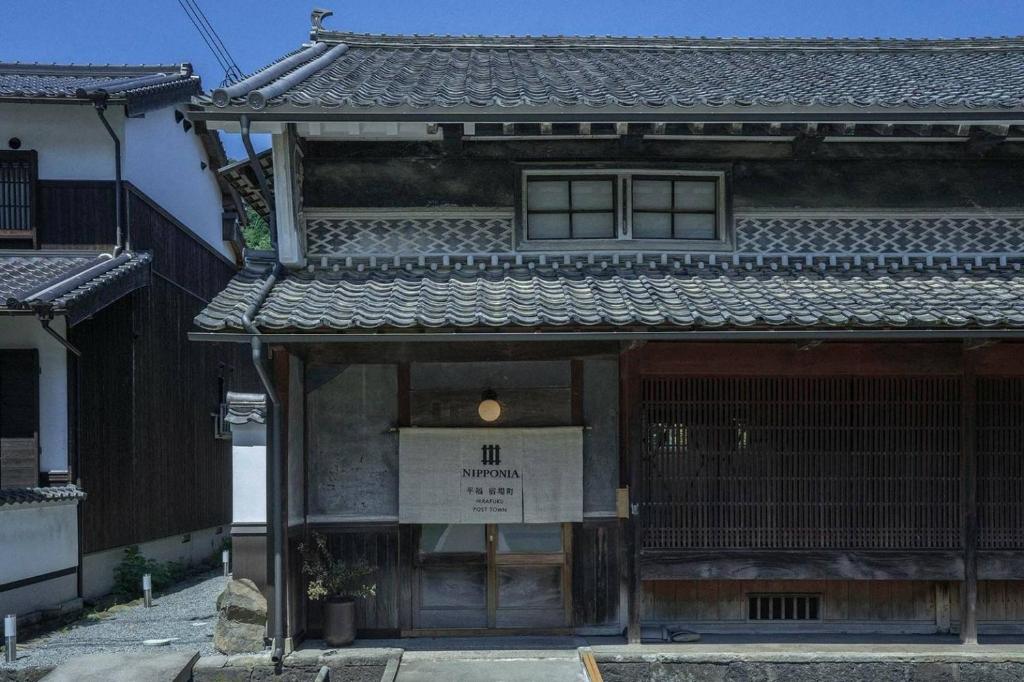 um edifício antigo com um sinal em frente em NIPPONIA平福宿場町 em Sayo