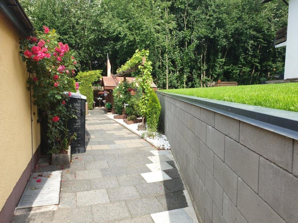 a walkway with flowers and a retaining wall at Ferienwohnung Helm in Wilnsdorf