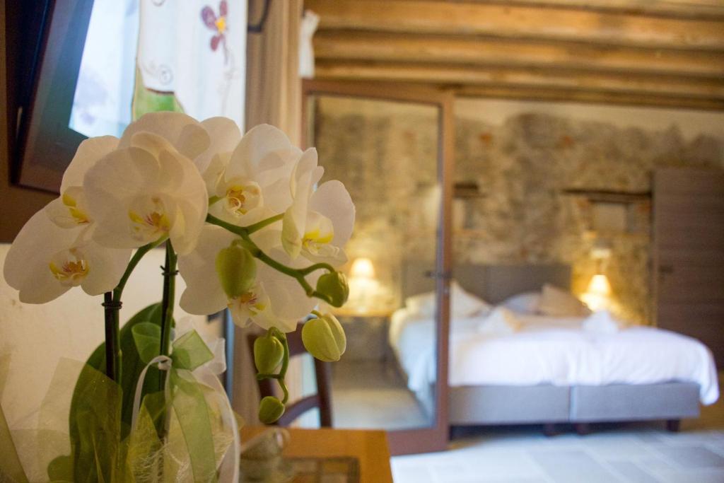 Agriturismo La Pina في Tarzo: مزهرية مع الزهور البيضاء أمام غرفة النوم