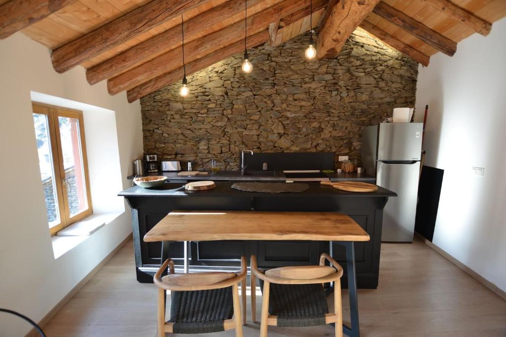 een keuken met een zwart eiland en een houten tafel bij Skyfall Maison in Valcebollère