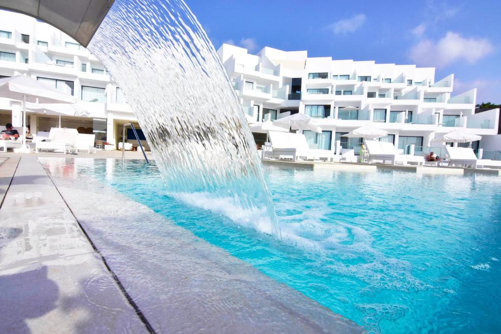 a fountain in front of a swimming pool with a building at Royal Marina Suites Boutique Hotel - Adults Only in Puerto Calero