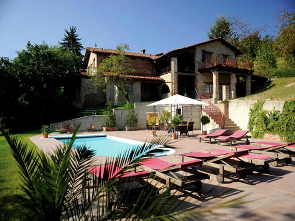 una casa con piscina con sedie a sdraio rosse di Apartment with large covered terrace in small residence with swimming pool a Bastia Mondovì