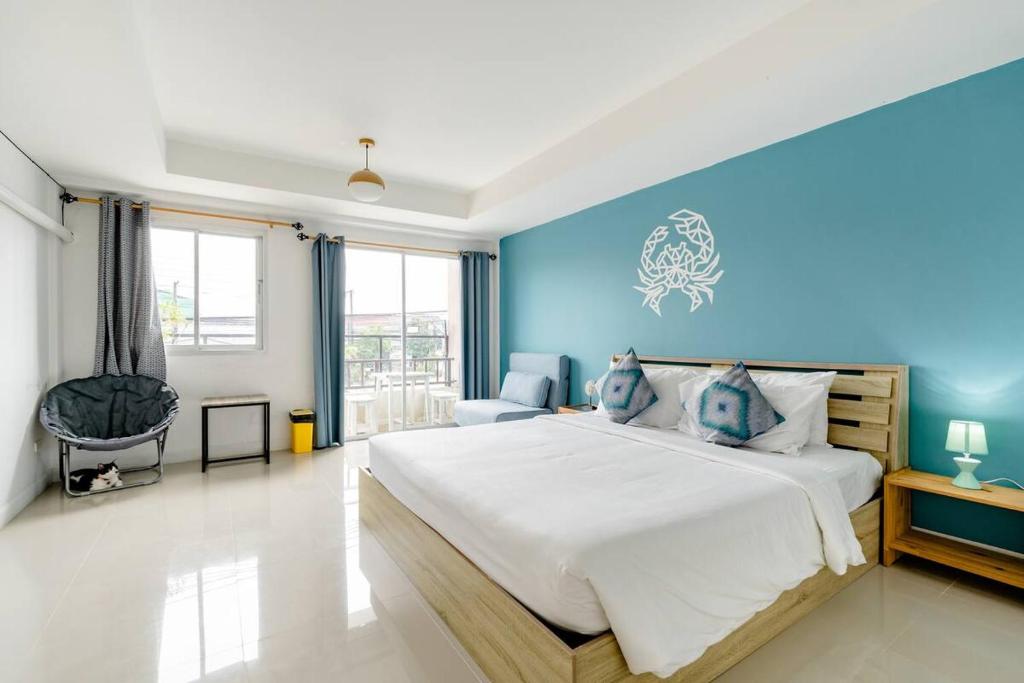 a bedroom with a large bed with a blue wall at Turtle Rooms in Bang Tao Beach