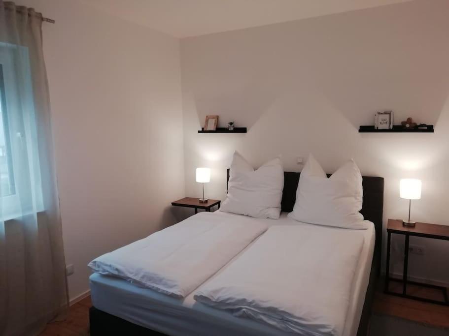 a bedroom with a white bed with two lamps on it at Premium Apartment mit Terrasse in Wörth