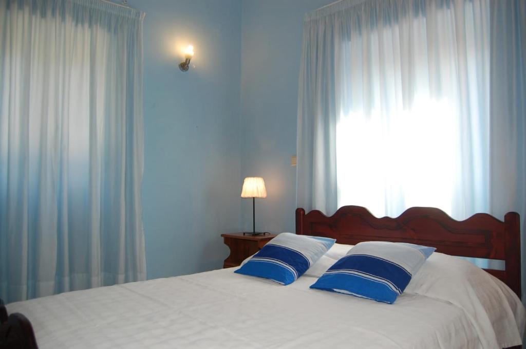 a bed with blue and white pillows and a window at Villa Korakades in Korakádes