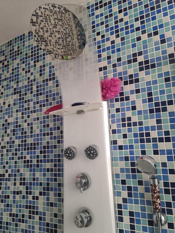 ein Bad mit einer Dusche mit blauen und schwarzen Fliesen in der Unterkunft Appartement à Montmartre in Paris
