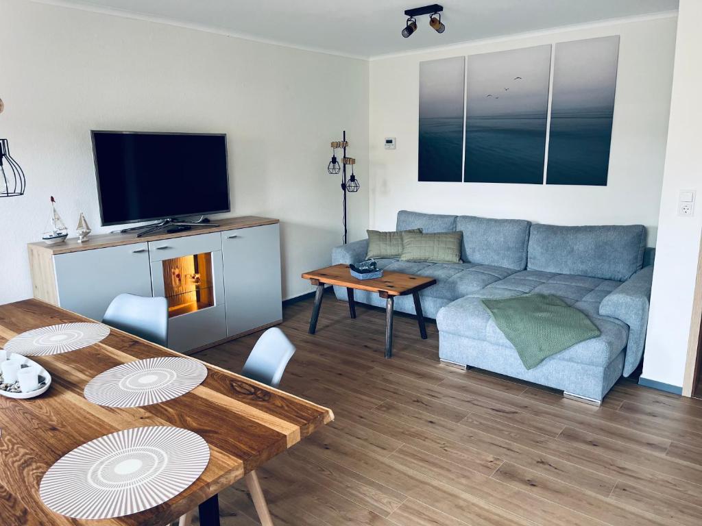 a living room with a blue couch and a table at Naturstrand Apartment - 86m² - 4 Betten - Parkplatz in Hagermarsch