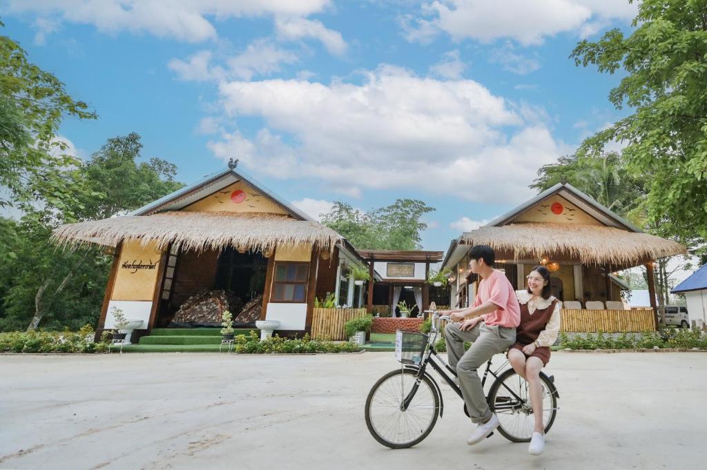two people riding a bike in front of a house at เชียงคานพาราไดร์รีสอร์ท&มีตติ้ง 