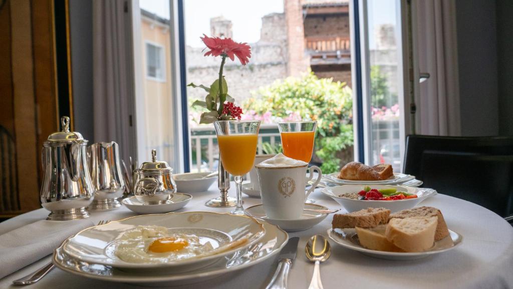 een ontbijttafel met eieren, brood en drankjes bij Hotel Villa Cansignorio in Lazise