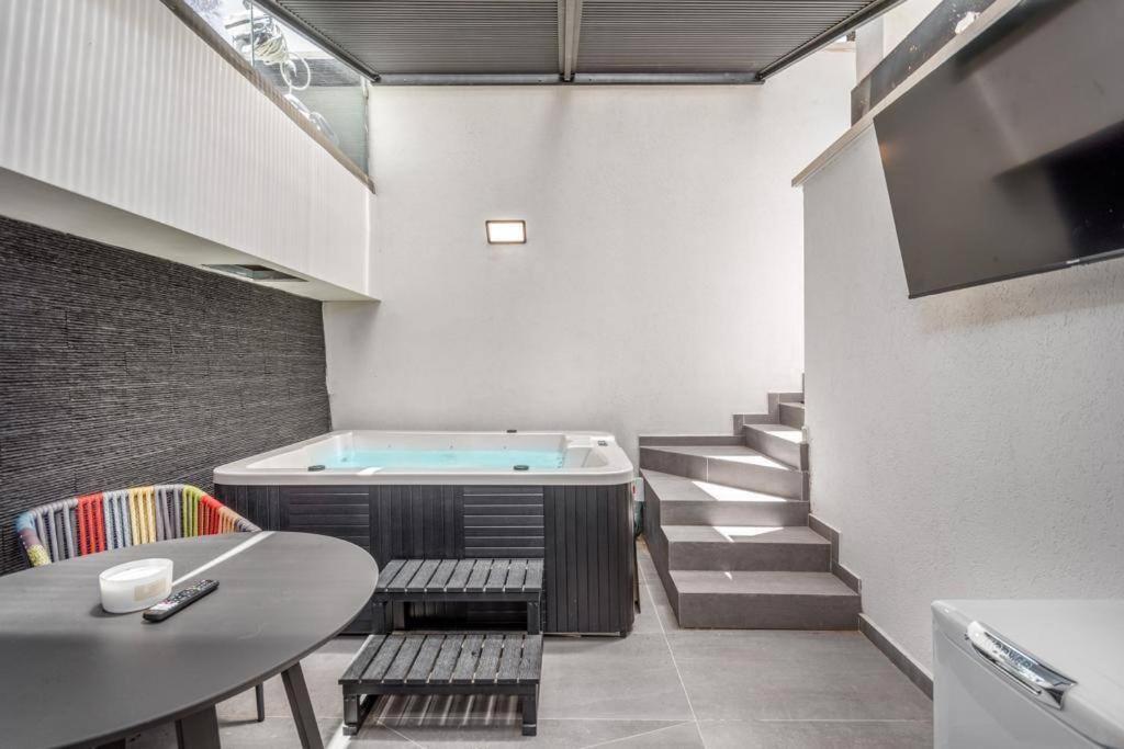 um quarto com uma banheira de hidromassagem, uma mesa e escadas em Hayarkon Park - Wonderful Private Jacuzzi em Tel Aviv