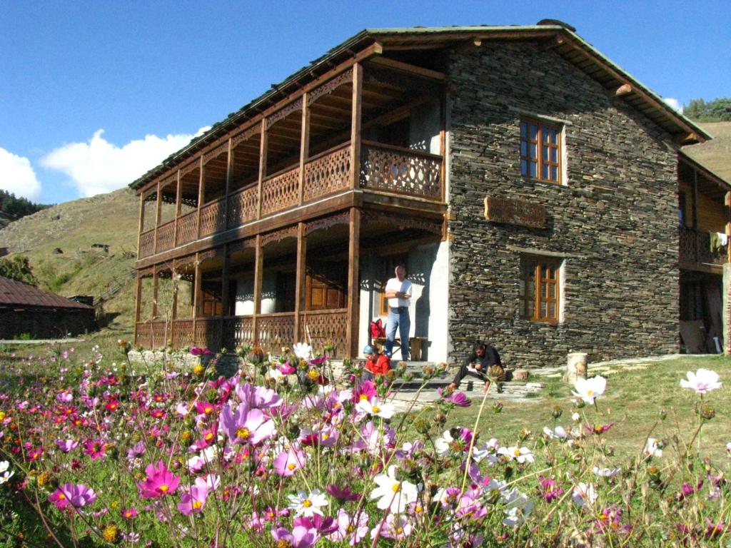a building with a balcony and a field of flowers at Guest House Shina in Omalo