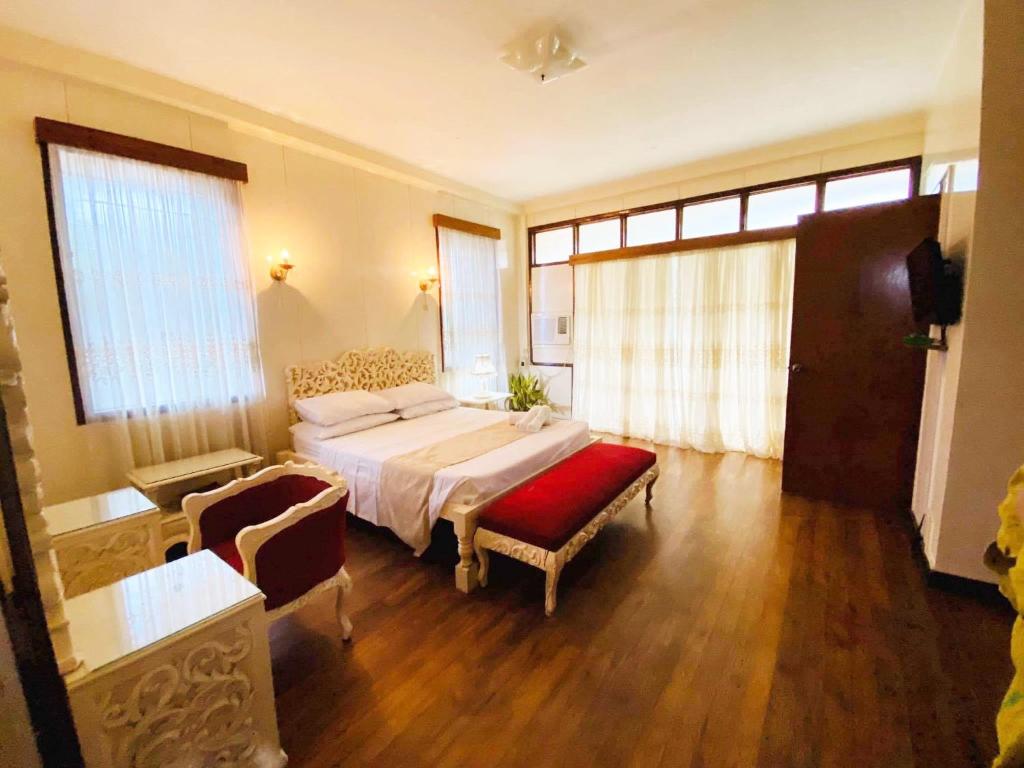 um quarto com uma cama, uma cadeira e janelas em Casa Don Julian Guesthouse em Bais