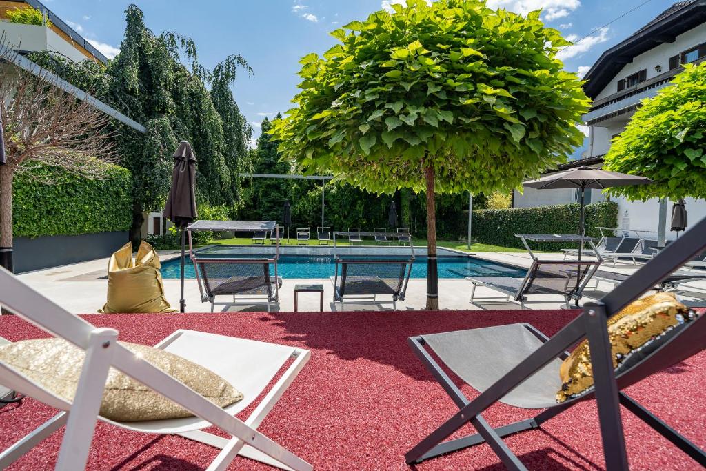 um pátio com piscina, cadeiras e uma árvore em goldfinger + suites em Lana