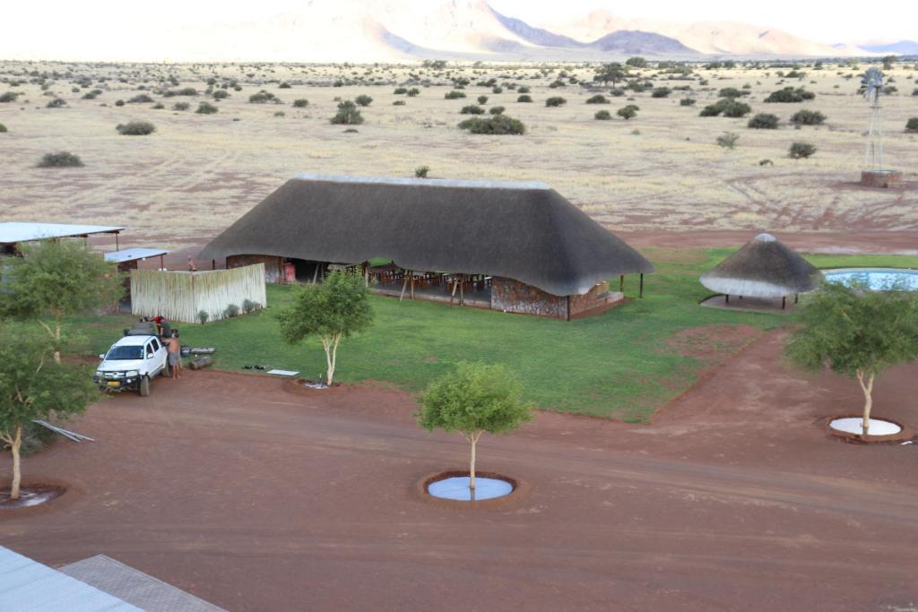 un grand bâtiment avec un toit de chaume dans un désert dans l'établissement Betta Camp, à Maltahöhe