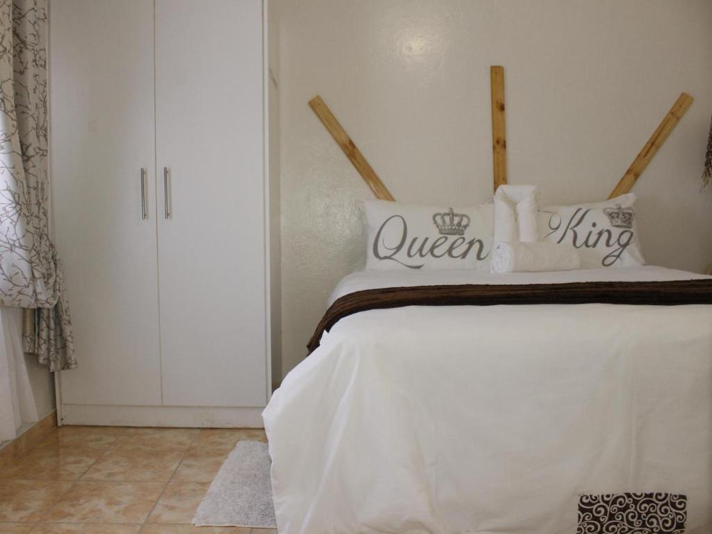 a bedroom with a white bed with a queen king sign on it at Abenab Lodge & Tours cc in Groutfontein