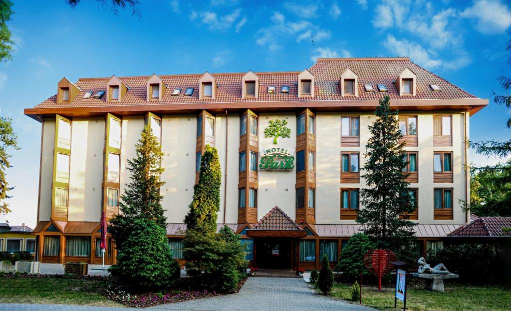 un grand bâtiment bien exposé avec un toit rouge dans l'établissement Park Hotel Gyula, à Gyula
