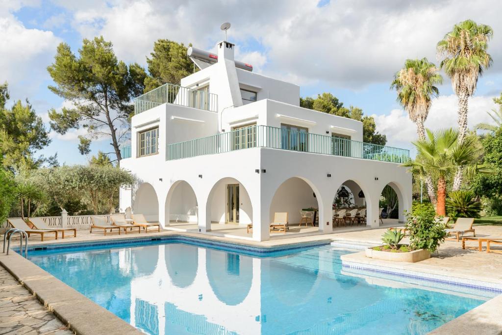 a white house with a swimming pool and palm trees at Villa Maria - Luxury Getaway in Ses Paisses