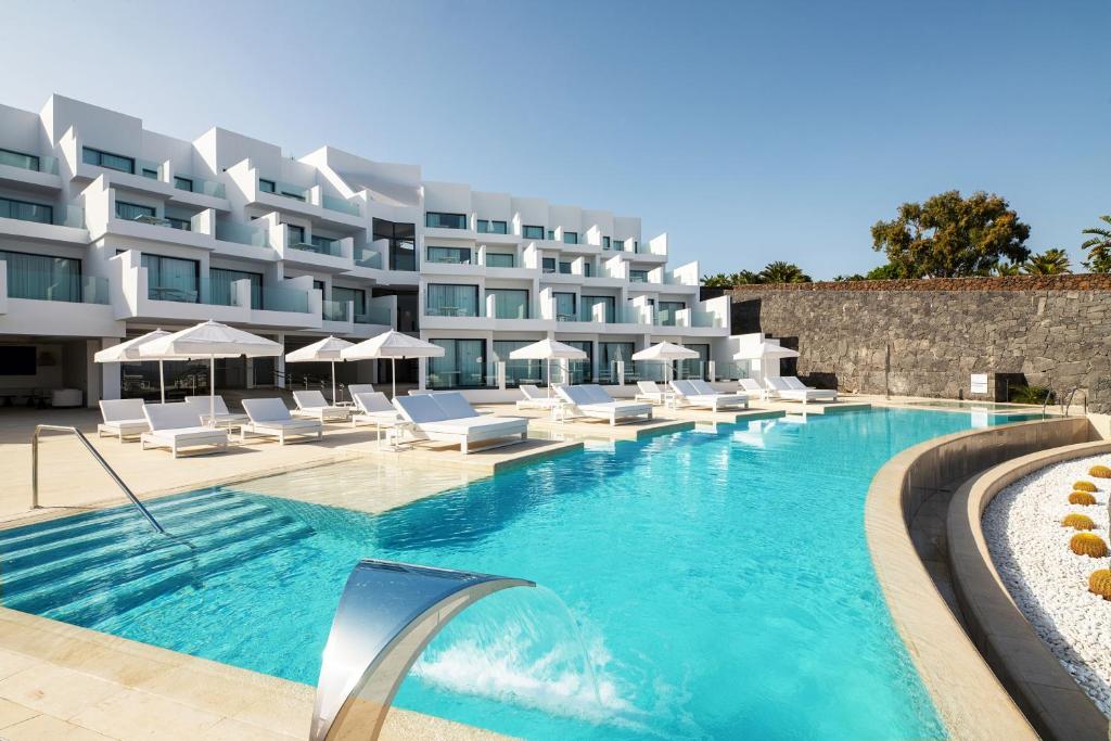 a hotel with a swimming pool with white lounge chairs at Royal Marina Suites Boutique Hotel in Puerto Calero