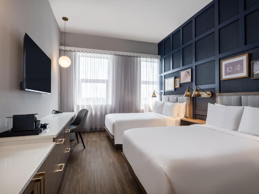 Habitación de hotel con 2 camas y escritorio en voco Fiorello - LaGuardia East, an IHG Hotel, en Flushing