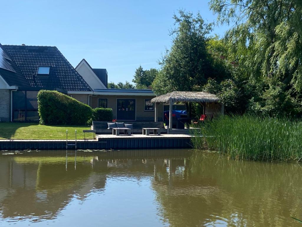 una casa con una mesa y un cenador junto a un lago en Wetterwillefriesland, en Wommels