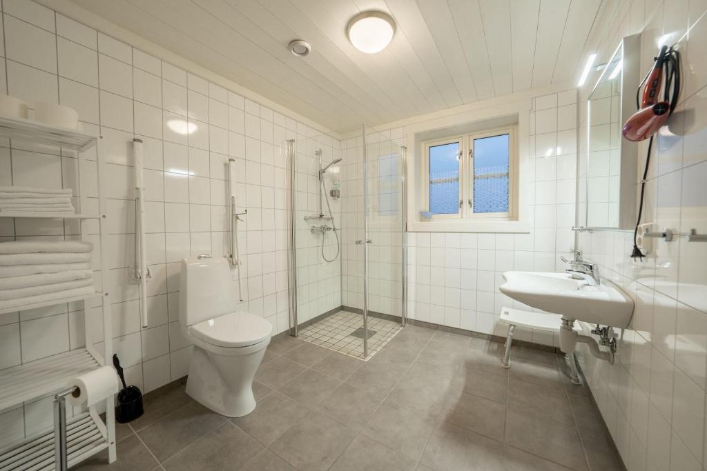a white bathroom with a toilet and a sink at Reinefjorden Sjøhus in Reine
