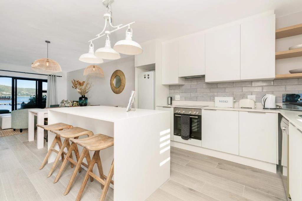 a kitchen with white cabinets and a large white island at Vista Laguna in Knysna