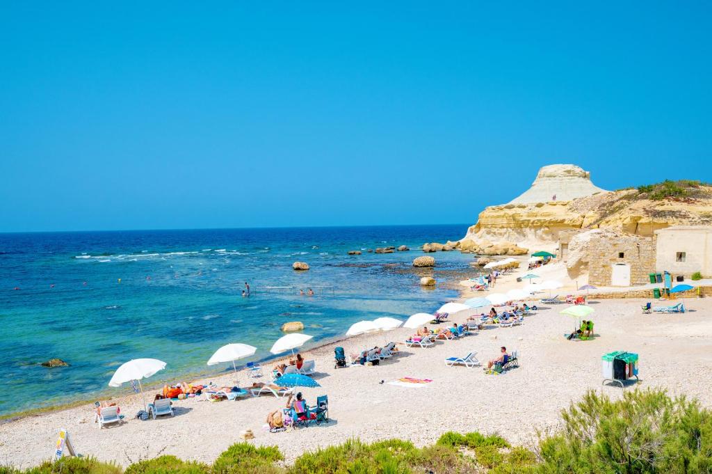 a group of people on a beach with the ocean at Salini Suites in Żebbuġ