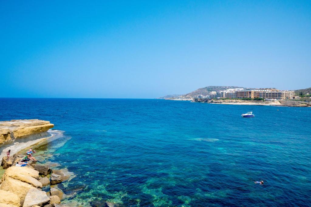 a group of people standing on the shore of the ocean at Salini Suites in Żebbuġ