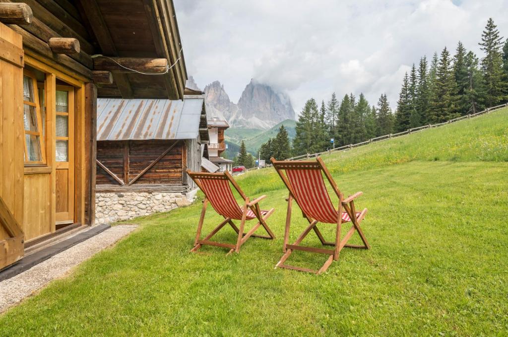 two chairs sitting in the grass next to a building at Baita Pecol Passo Pordoi in Canazei