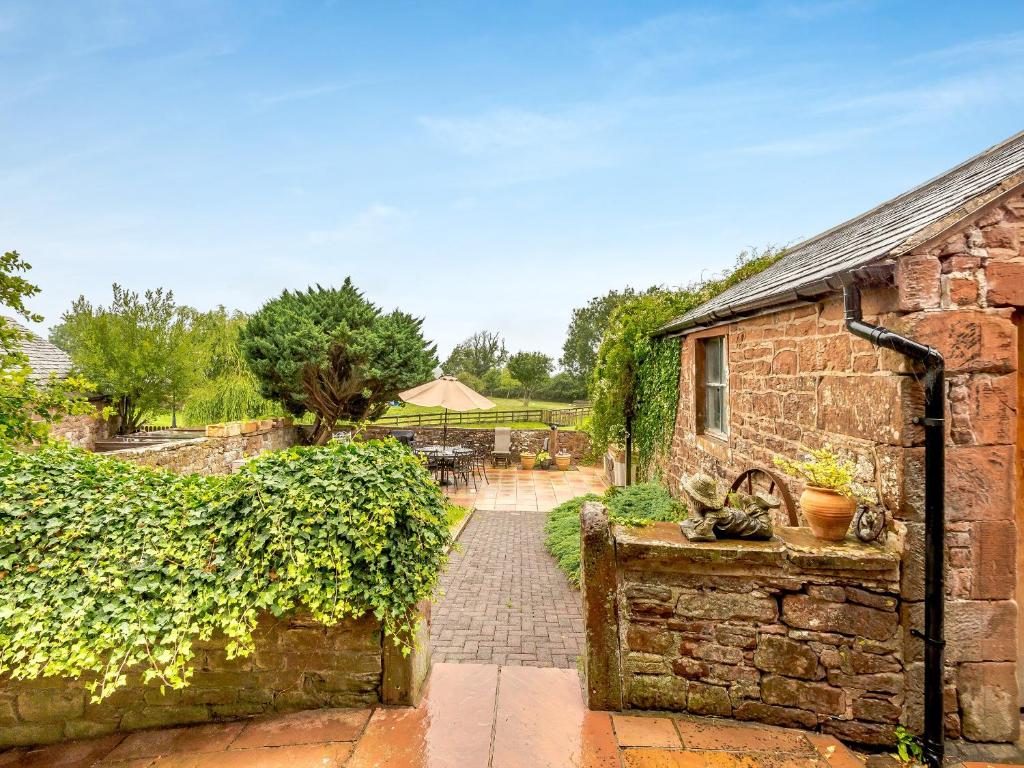 a stone house with a brick pathway leading to a building at Halls Bank Farm in Aspatria