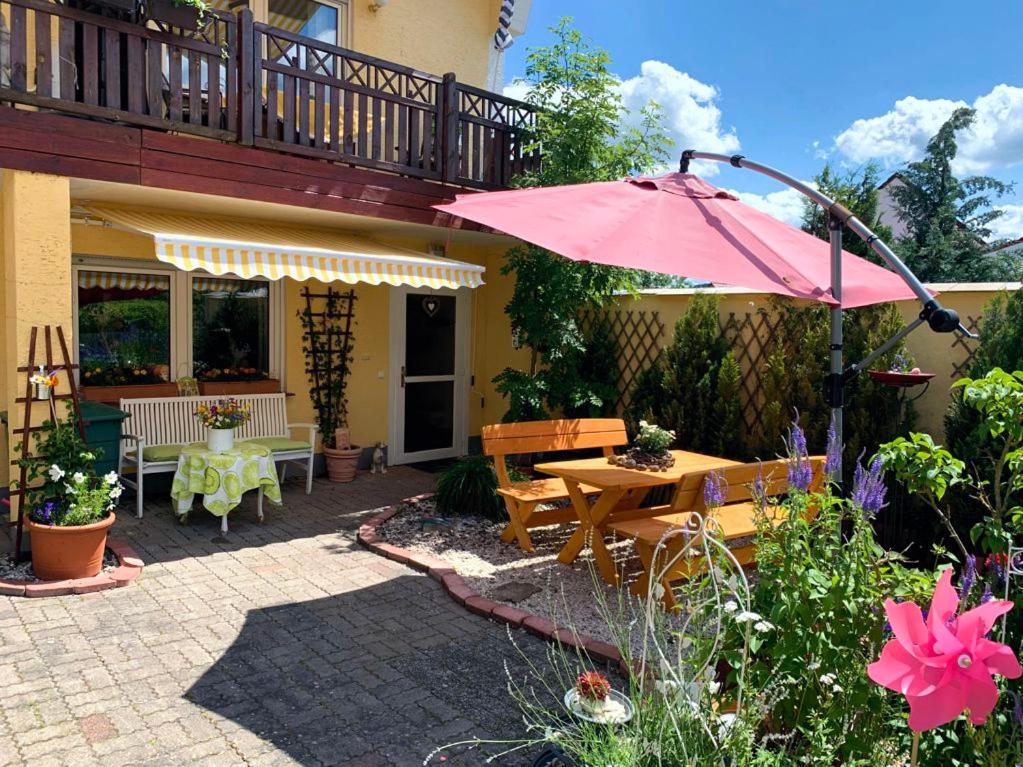 Germerode的住宿－Ferienwohnung Mohnbrise，一个带桌子和粉红色遮阳伞的庭院