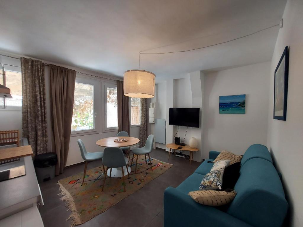 un salon avec un canapé bleu et une table dans l'établissement Gretta - Patio, Cosy, WiFi - Ajaccio, à Ajaccio