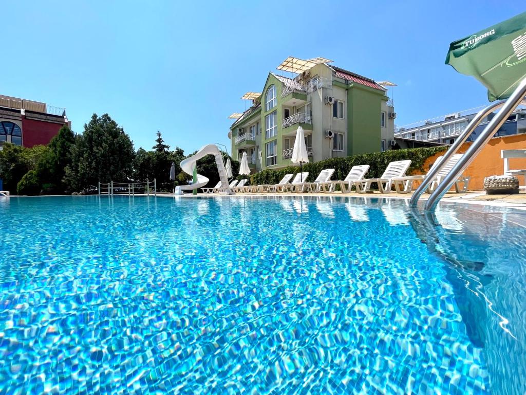 a large swimming pool with blue water and chairs at Mint Family Hotel in Ravda