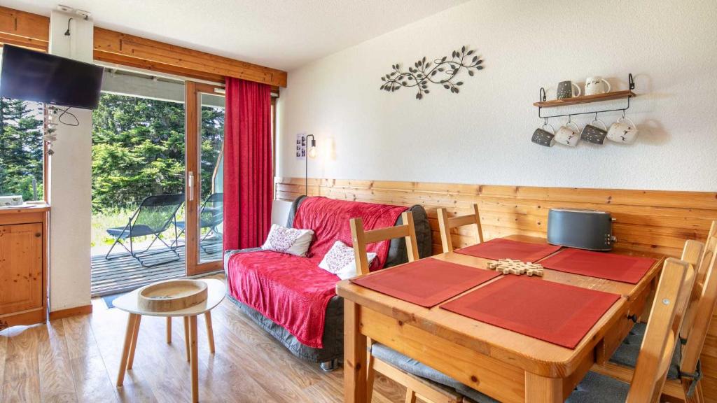 ein Wohnzimmer mit einem Tisch und einem roten Sofa in der Unterkunft V du Bachat Arolles A03 - Appt 4 pers in Chamrousse