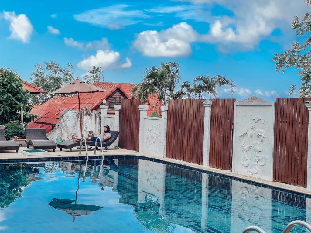 une femme assise sous un parasol à côté d'une piscine dans l'établissement Bounty Resort, à Haad Son