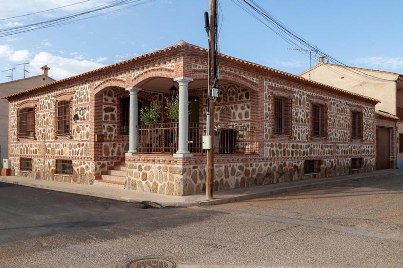 - un bâtiment en briques avec une véranda et des colonnes dans une rue dans l'établissement Los olivares de Rober, à Polán