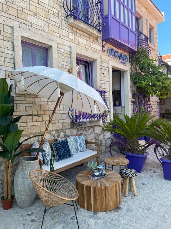 a patio with a bench and a table and an umbrella at alba otel in Ildır