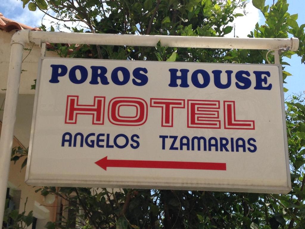 een bord voor een pocos house hotel met een rode pijl bij Poros House Hotel in Póros