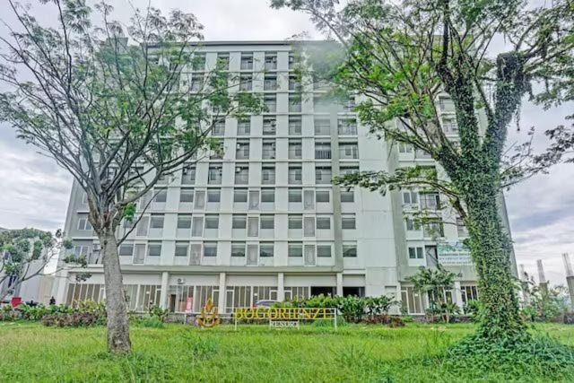 un grand bâtiment blanc avec des arbres devant lui dans l'établissement Apartment Bogorienze, à Bogor