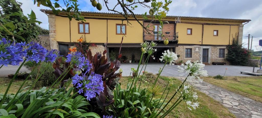 a yellow building with flowers in front of it at CASERIO EL AJO in Santillana del Mar